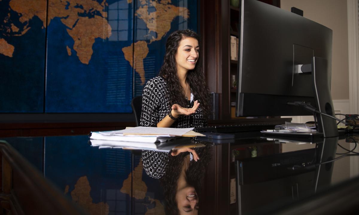 Image of a young girl sitting at a desk smiling. 