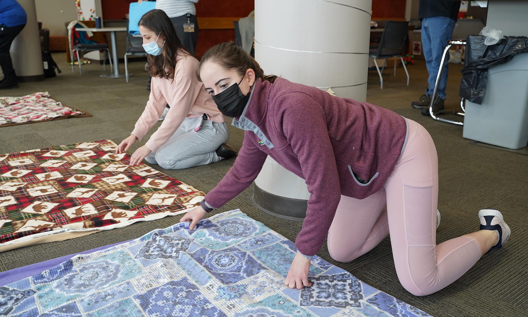 An image of a student making a tie blanket.