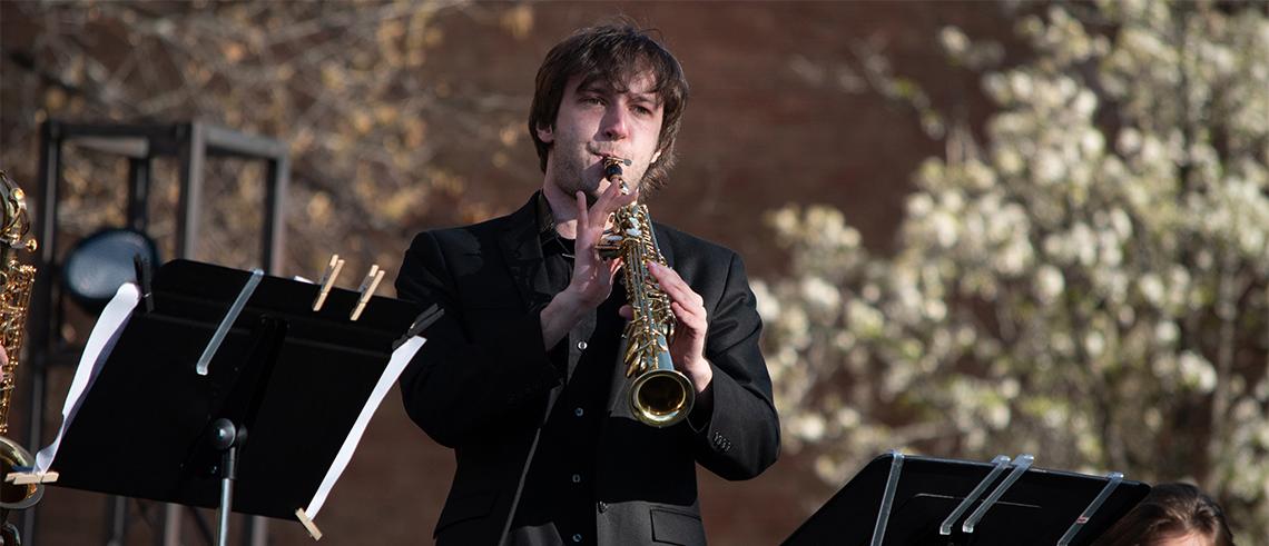 Male student playing brass instrument on stage
