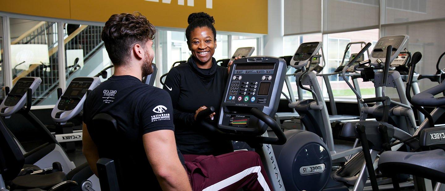 trainer working with a client on an exercise bike in a fitness center