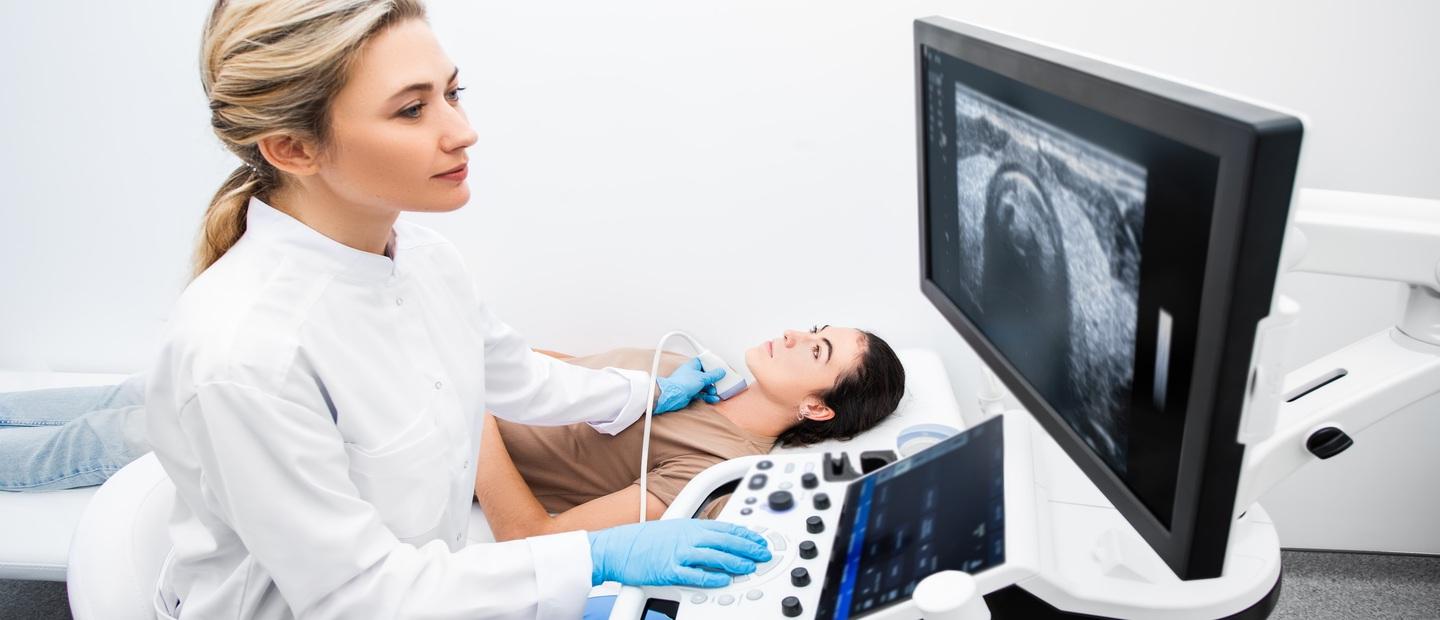 A sonographer imaging a woman's throat.