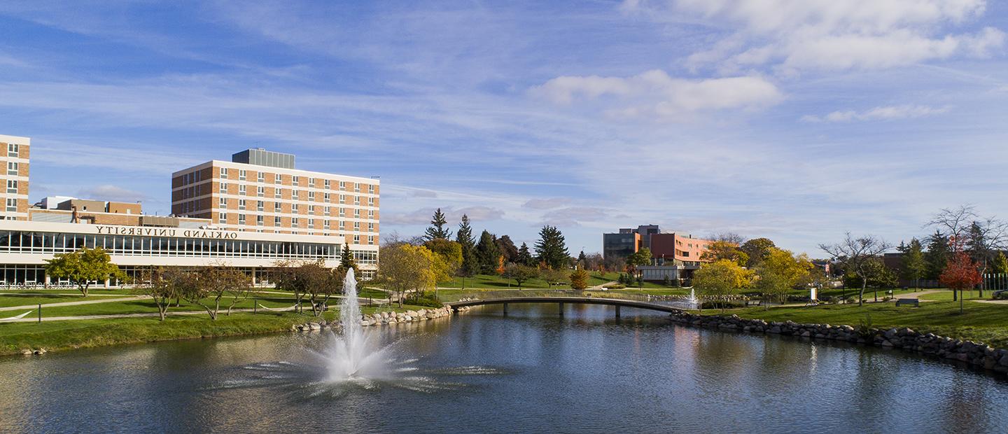 image of Oakland University's campus with a view of Bear Lake, Vandenberg Hall and the Human Health Building